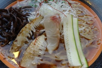 The topping is two slices of grilled bamboo shoot, sliced zucchini, seaweed, long green onion, and one slice of tai sashimi (raw fish).