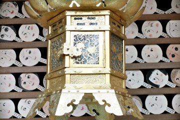 <p>Another lantern near a wall of prayer signs in the shape of hand-mirrors</p>