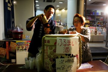 <p>This hospitable couple were handing out delicious sake for free, but they had to pause to refill the barrel</p>