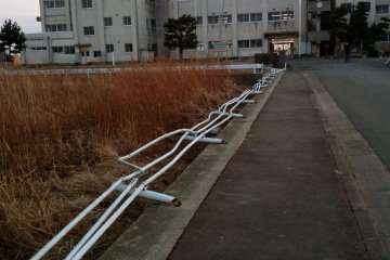 <p>The approach to&nbsp;Yuriage&nbsp;Middle School. The steel guard rail is bent at an impossible angle from the force of the rushing debris-filled water.</p>