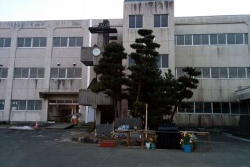 <p>A small monument in front of the school provides a place to pray and reflect. Meanwhile a clock on the outside of the building has not moved since March 11th, 2011 2:46PM, the time the earthquake struck.&nbsp;</p>