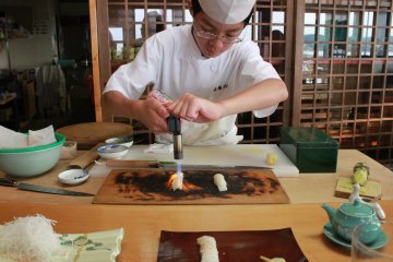<p>Motoshige searing the top of the fish with a torch.&nbsp;</p>