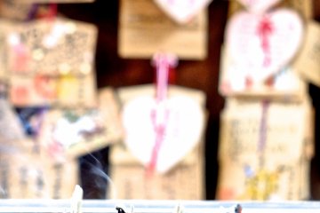 <p>Incense sticks offered up for prayer; in the background are prayer boards</p>