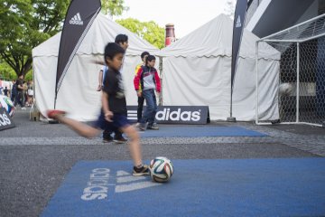 A young boy trying to knock pins with his football skills.