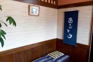 <p>Waiting area near the entrance. Hanging scroll says, 'Arigato - Thank you'</p>