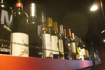 Wine stored on a shelf over the bar, safely out of the comedians' reach