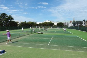 <p>Blue sky and green field of the tennis court</p>