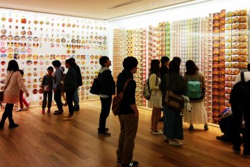 <p>Visitors browse the walls of past instant noodle package designs.&nbsp;</p>