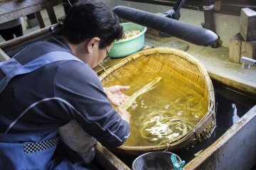 Seorang wanita tua dengan susah payah membersihkan kulit kayu murbei yang digunakan untuk membuat washi