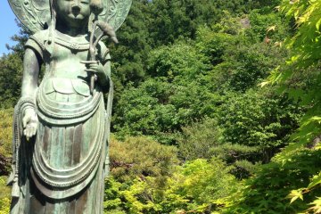 <p>Mini Buddha&nbsp;statue in front of the red bridge and koi pond that are part of the temple grounds</p>