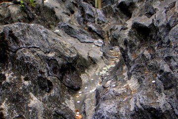 Visitors throw coins onto the unusual rock formations