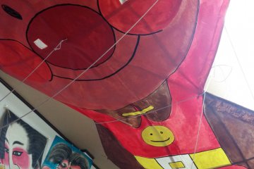 <p>An Anpanman character hovers over the workbench at the Kesennuma&nbsp;kite club's storage building</p>