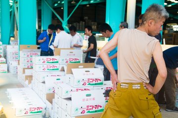 <p>Men line up to buy cases of fruit and vegetables</p>