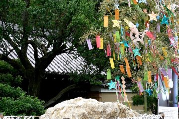 <p>A sacred rock with a fence of fortune papers tied onto string</p>