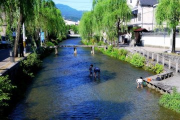<p>Pada musim panas yang panas di Kyoto, orang tua membawa anak-anak mereka bermain di sungai yang dangkal</p>