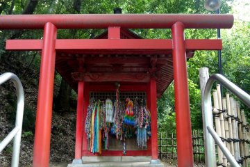 <p>Small shrine hung with strings of origami cranes</p>