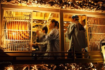 <p>Musicians playing drums and flutes inside the Yatai</p>