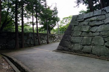 <p>Left behind castle walls flank the now concrete path</p>
