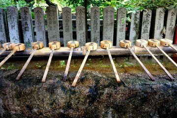 <p>Many bamboo scoops lie across the water basin for purifying hands</p>