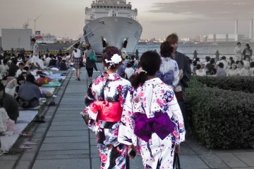 <p>A couple of young women wait patiently for the display to begin near the 'Aka-Renga' area. Note the large ship in the background that belongs to the Japanese Coast Guard, which maintains a small patrol base here</p>