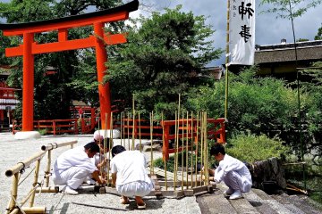 <p>Shinto priests making a wooden stand for a ceremony near Mitarashi-no-ike</p>