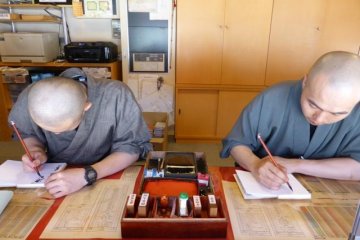 Para biksu melukis Goshuinchou di seberang kuil merah besar (Konpon Daito) di Koyasan