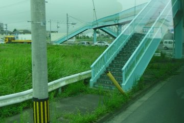 <p>This is a view of the pedestrian bridge that students used to use to get to school. When the tsunami hit, 15 people took refuge up here, spending the night in the cold. They tried to rescue others carried along by the water, but they died in the night. A helicopter in the area couldn't help them due to the spurts of flames coming from boats washed inland.</p>