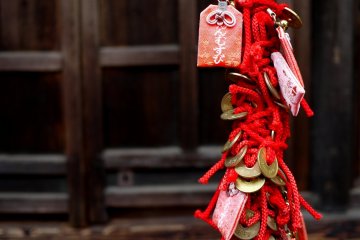 <p>Small charms and five yen coins woven into a decorative rope</p>