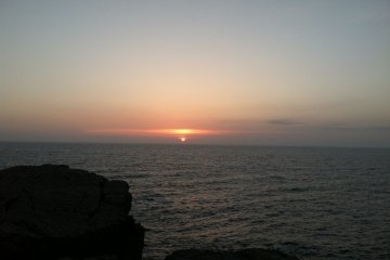 <p>The sky comes alive as the sun sinks behind the sea</p>