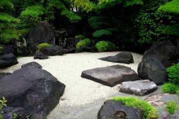 <p>Rocks and sand form a small dry garden</p>