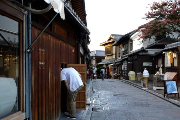<p>A restaurant worker ducks through a small door in the wooden wall</p>