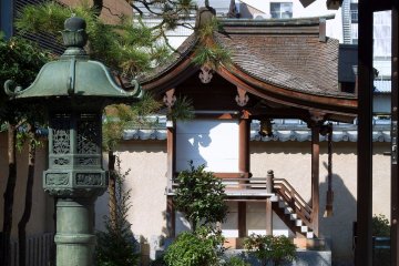 <p>Bronze lantern of Shibata Shrine with Three Sisters Shrine in the backdrop</p>