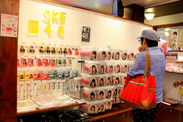 <p>Fans pria AKB48 melihat gantungan kunci dan pernak pernik lainnya sambil menatap foto personilnya.&nbsp;</p>