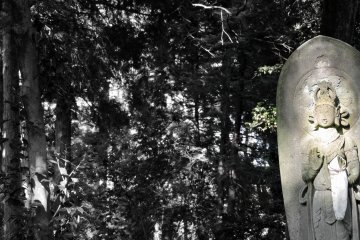 <p>Divine statue of Kannon Bosatsu in a serene forest setting</p>