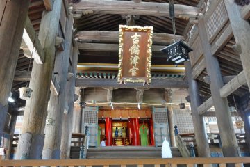 <p>The wooden pillars with decorative metal ring supporting beams inside the main building</p>