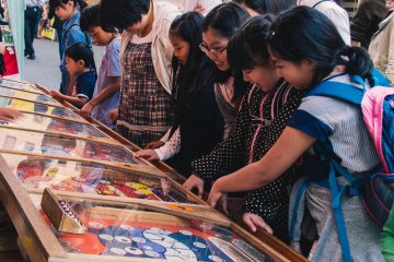 <p>A group of girls playing a pinball game.</p>