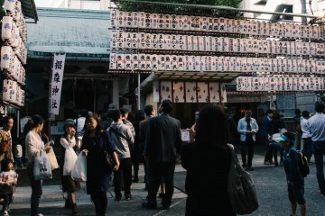 <p>Shinto temple surrounded by lanterns and people.</p>