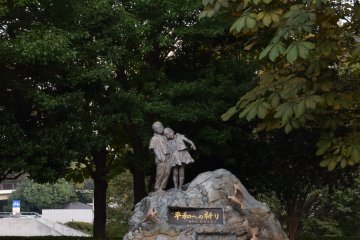 <p>A kid riding past a statue of two kids</p>
