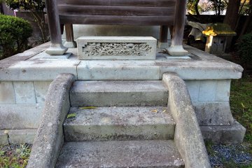 <p>Small wooden shrine is placed on a stone pedestal</p>