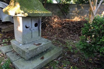 <p>Small moss-covered stone shrine in the corner of the grounds</p>