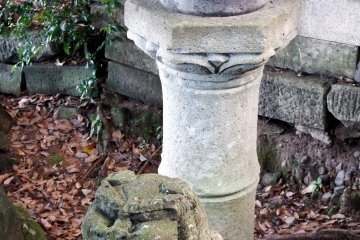 <p>The other guardian dog sitting sheepishly at the foot of a stone lantern</p>