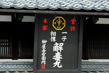 <p>Black wooden sign of an apothecary shop</p>