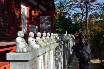 Temple lined with little Buddhas all around the building. People offer prayers and coins to the little Buddhas.