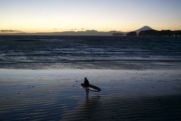 <p>A surfer coming out of the water with Mt. Fuji in the background</p>