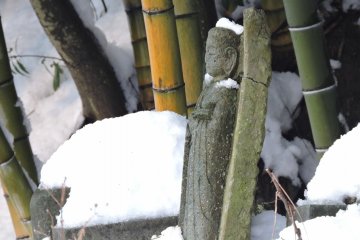 <p>Broken Jizo statue standing forlornly in a Jizo cemetery covered with snow</p>