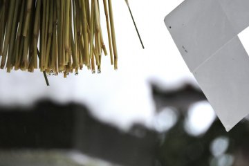 <p>Water droplets on the sacred straw hanging from the stone torii gate</p>