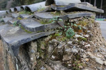 <p>Old tiles make up an old Japanese wall</p>