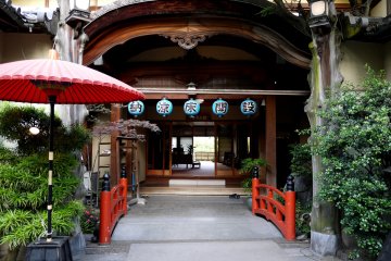 <p>A red bridge is echoed by a red umbrella in this rather grand restaurant entrance</p>