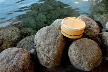 Small tub resting on natural boulders that edge the bath