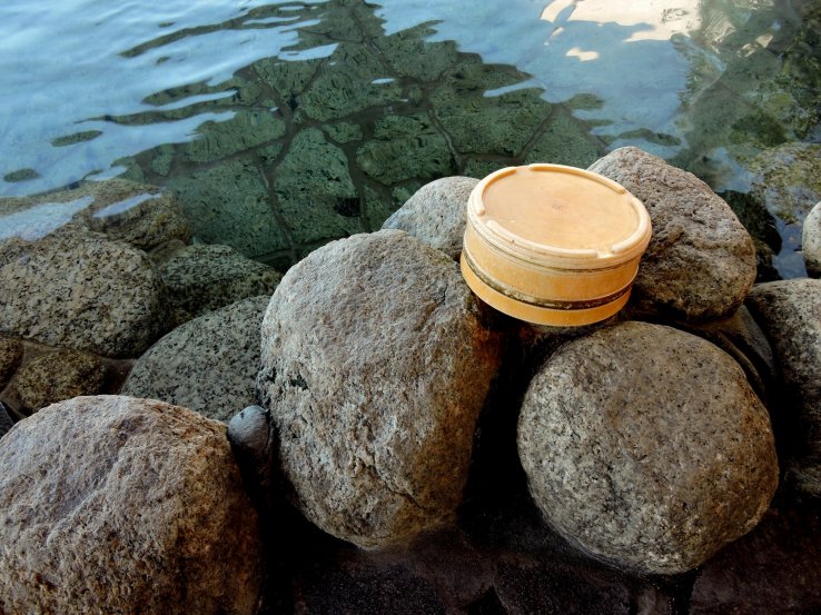 Small tub resting on natural boulders that edge the bath